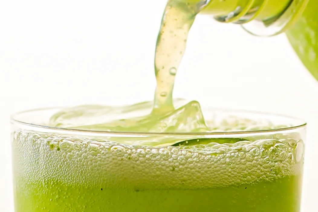 A green drink being poured into a glass