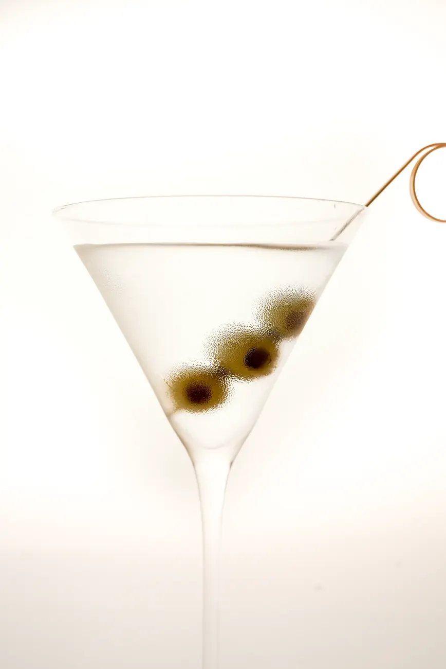 A martini glass with olives on a pick
